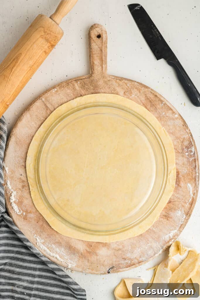 Rolled and trimmed pie crust perfectly shaped under a pie plate on floured board