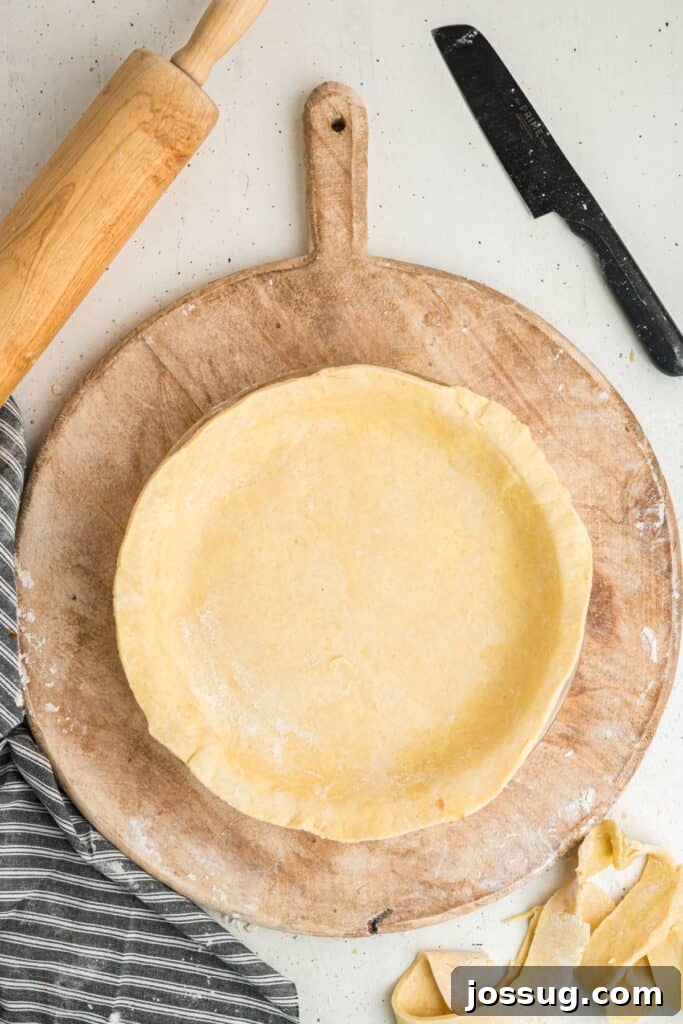 Unbaked pie dough pressed into a pie dish, ready for trimming and crimping