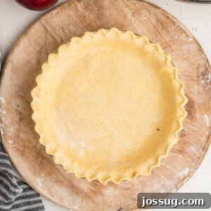 Square image of crimped butter pie crust in a glass pie dish, ready to bake