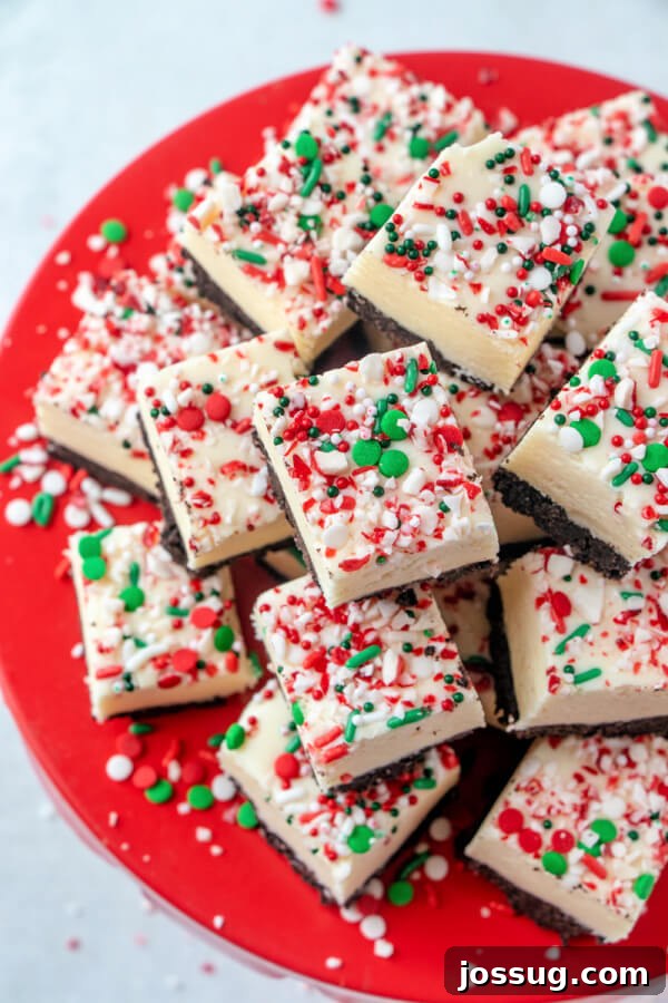 Looking down onto a plate of perfectly cut white chocolate peppermint fudge squares, adorned with festive sprinkles.