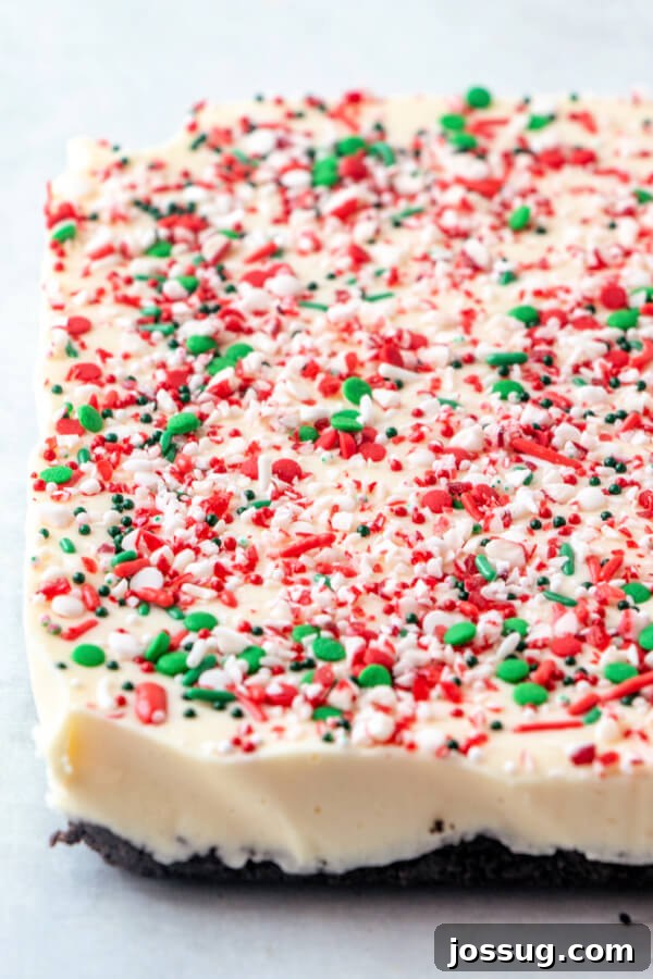 A freshly made slab of white chocolate peppermint fudge, glistening and ready to be sliced into individual pieces.