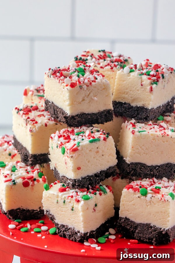 Multiple pieces of white chocolate peppermint fudge, neatly stacked on a festive plate, inviting a bite.