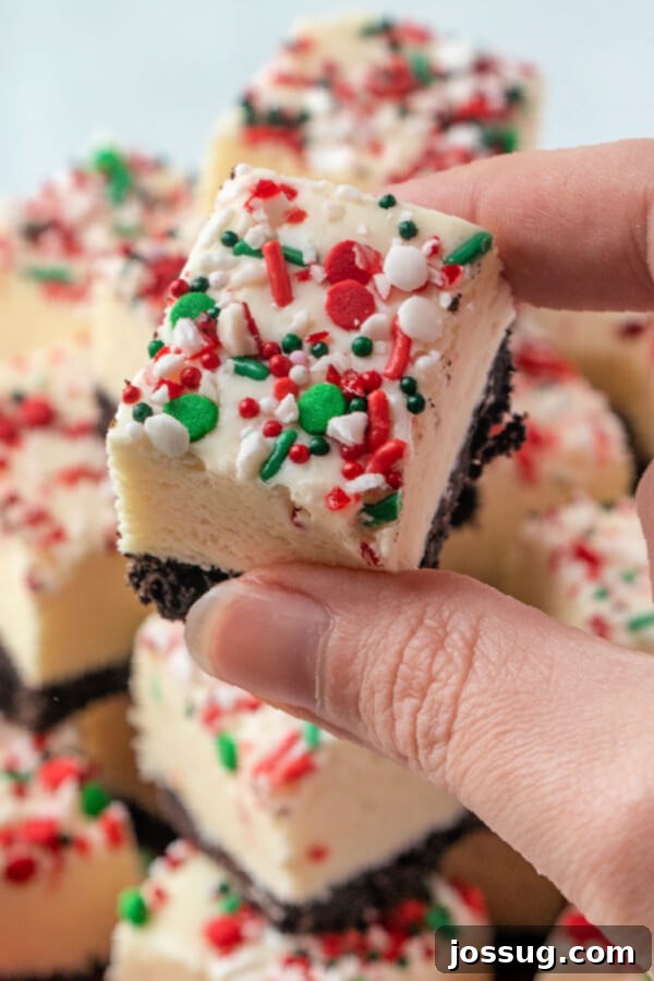 A hand holds a single piece of finished white chocolate peppermint fudge, ready to be enjoyed.
