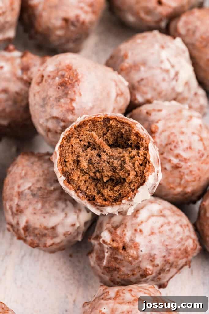 Overhead shot of glazed chocolate donut holes with one donut cut open