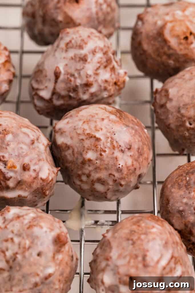 Glazed chocolate donut holes resting on a wire cooling rack