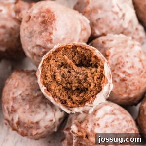 Square image of glazed chocolate donut holes with one cut open to show inside