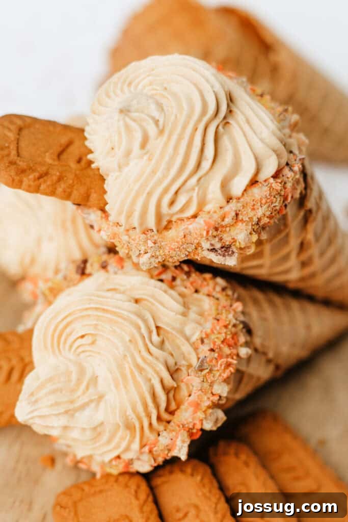 Two finished pumpkin cheesecake cones with piped filling and Biscoff cookies on top, showcasing a delightful fall dessert.
