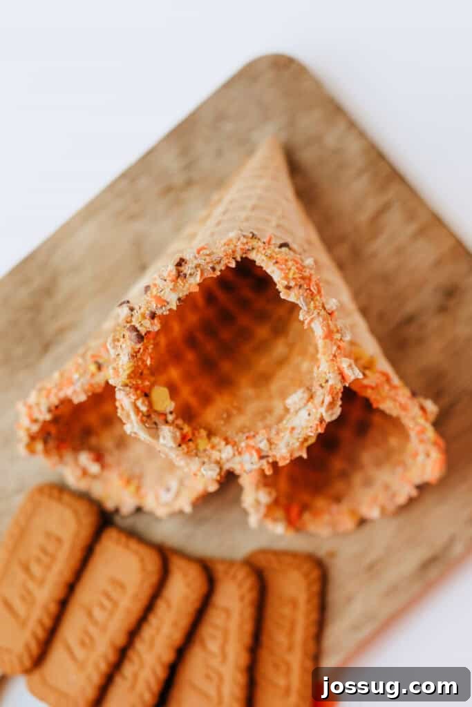 Close-up of waffle cones with rims generously coated in crushed Reese’s Pieces, highlighting the crunchy candy topping.