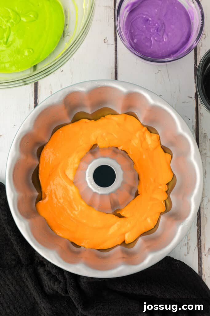 Bewitched Bundt Cake 11 Orange cake batter spread evenly in the bottom of a greased bundt pan for Halloween Bundt Cake base layer.