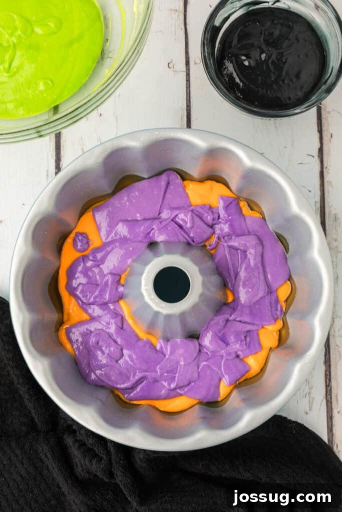 Bewitched Bundt Cake 12 Purple cake batter layered on top of orange batter in a bundt pan for Halloween Bundt Cake.