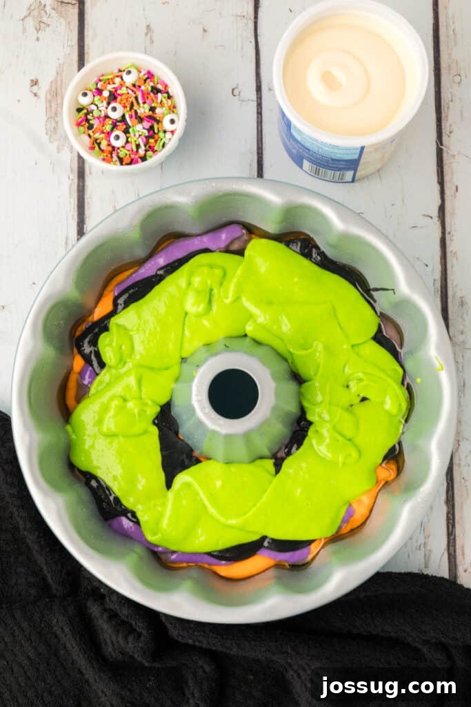 Bewitched Bundt Cake 14 Bundt pan filled with green cake batter on top of purple, black, and orange layers for Halloween Bundt Cake.