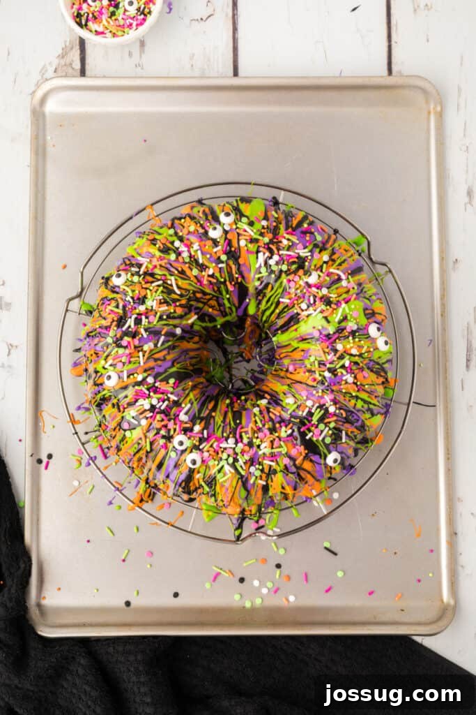 Bewitched Bundt Cake 23 Finished Halloween Bundt Cake on a wire rack, topped with colorful drizzles and festive sprinkles with candy eyeballs.
