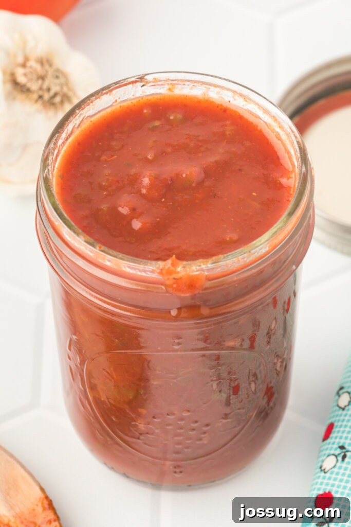 closeup of jar filled with homemade enchilada sauce, showcasing its rich, reddish-brown color and smooth texture