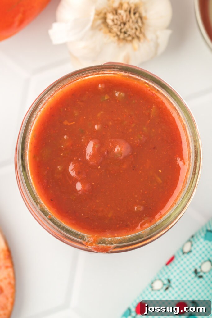 looking down into a jar of enchilada sauce, displaying its smooth texture and appetizing color