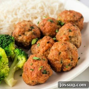 Square crop of golden brown air fryer chicken meatballs served with broccoli and rice, garnished with fresh parsley