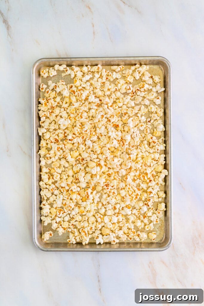 Large baking sheet generously filled with fluffy, plain air-popped popcorn, evenly spread and ready to be coated with the warm, buttery caramel sauce.