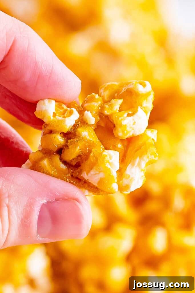 Close-up of hands gently holding a cluster of perfectly crunchy, golden caramel corn, showcasing its inviting texture, rich color, and irresistible appeal.