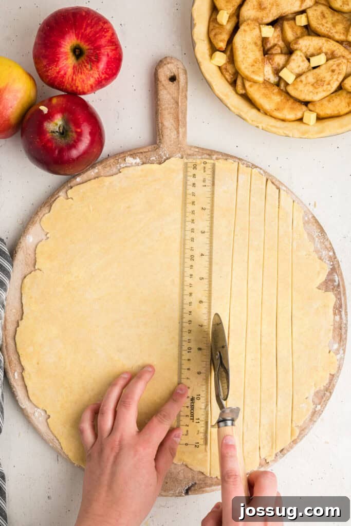 Skilled hands measuring and cutting strips of pie dough with a ruler and a specialized pastry wheel, ensuring uniform strips for a beautiful lattice top.