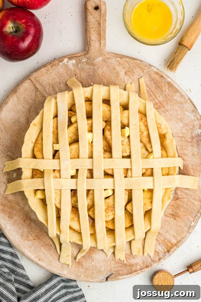 A top-down view of a meticulously crafted apple pie, featuring a perfectly woven lattice crust, now fully assembled and ready for its journey into the oven.