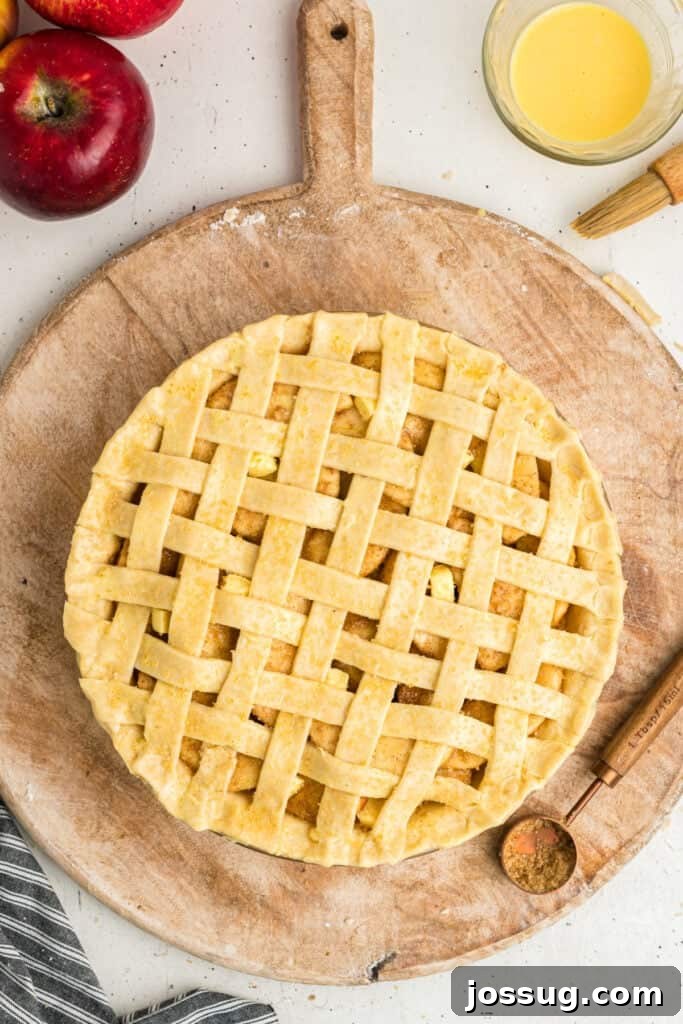An unbaked lattice crust apple pie, generously sprinkled with sparkling coarse sugar, now perfectly prepared and poised to enter the oven for baking.