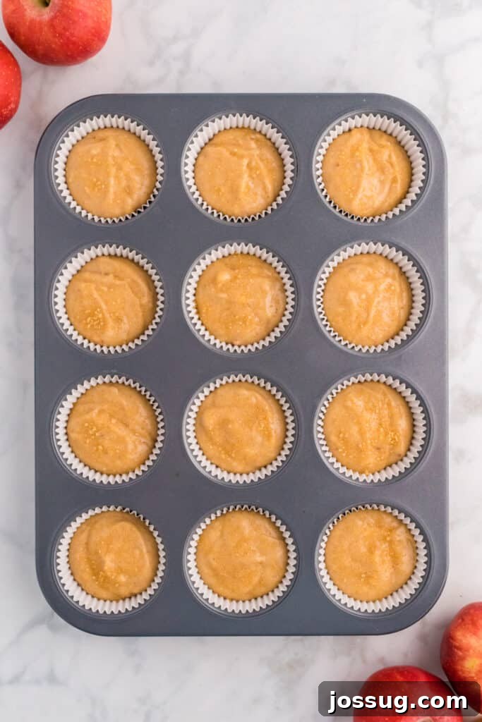 Cider Mill Muffins 9 Muffin pan filled with apple cider muffin batter before baking, sprinkled with coarse sugar on top.