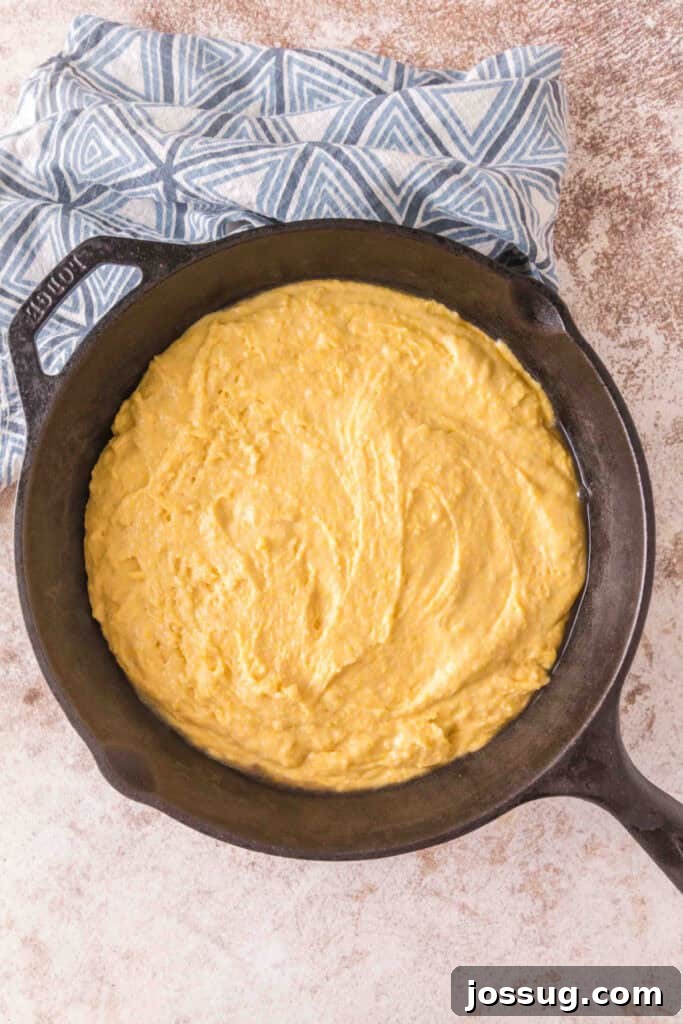 Cultured Cornbread 14 Raw cornbread batter spread evenly in a hot cast iron skillet before baking.