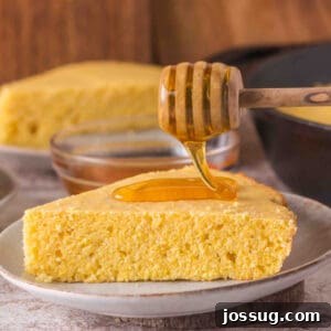 Square crop of a golden cornbread slice on a plate with a honey dipper, ready to be served. Perfect for sharing on social media.