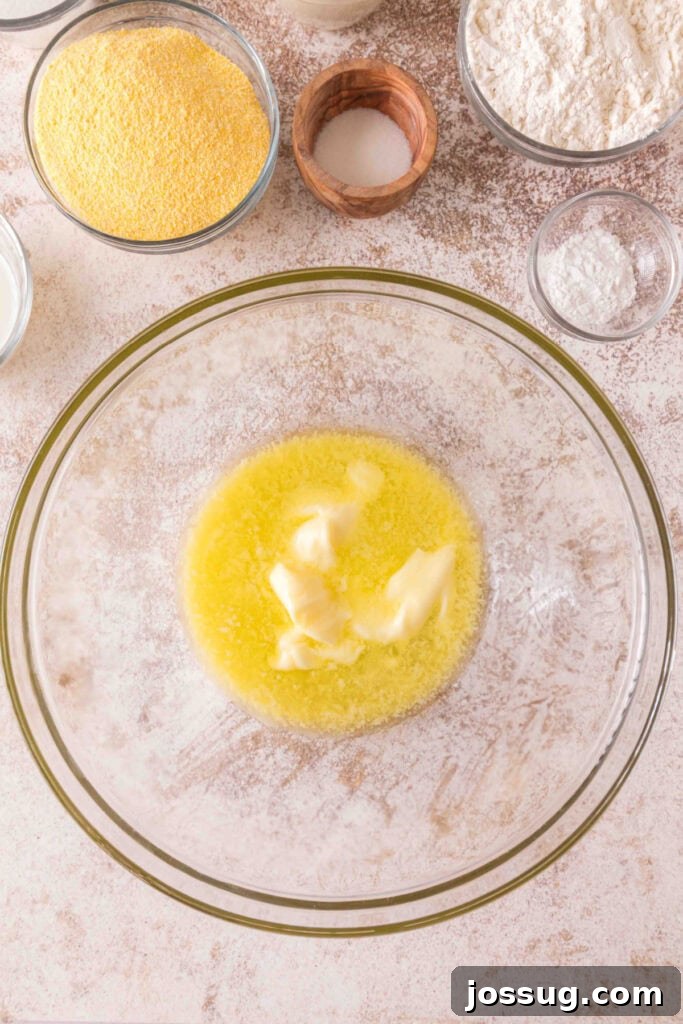 Cultured Cornbread 4 Mixing bowl with melted butter beginning to soften, surrounded by dry ingredients for cornbread.