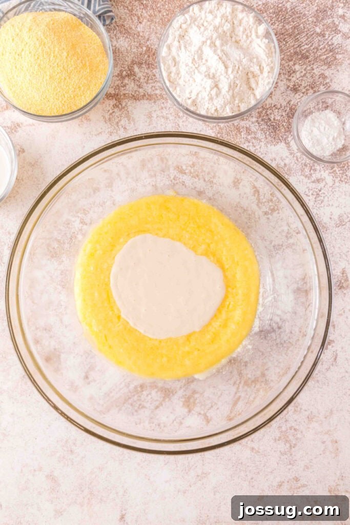 Cultured Cornbread 7 Sourdough discard starter added to the wet mixture of butter, sugar, and eggs in a glass bowl.