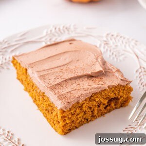 Square close-up of a pumpkin bar topped with Nutella buttercream on a white plate, emphasizing the rich frosting and moist crumb.