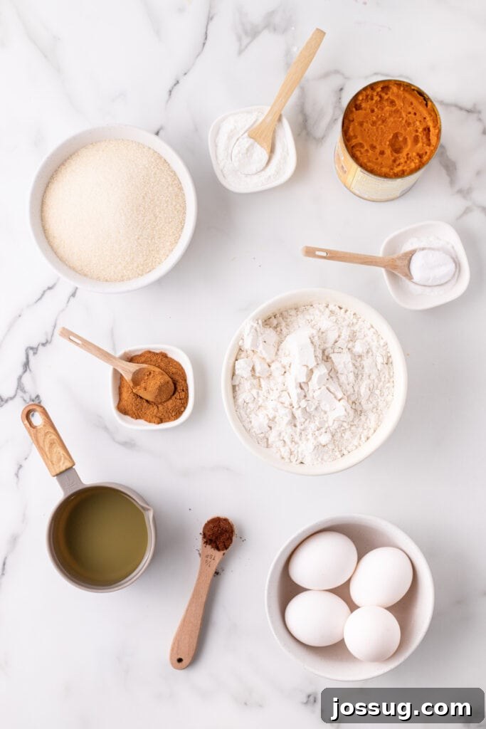 Overhead view of measured ingredients for pumpkin bars including flour, sugar, pumpkin puree, eggs, oil, and spices on a marble countertop, ready for mixing.