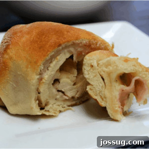 Chicken Cordon Bleu Crescent Rolls on a white plate, with one roll bitten into.