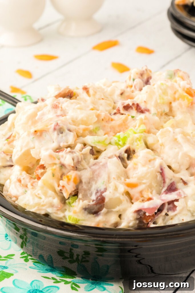 Close-up of creamy Bacon Ranch Potato Salad in a sleek black bowl, garnished with fresh green onions and crispy bacon bits, ready to be served at a summer gathering.