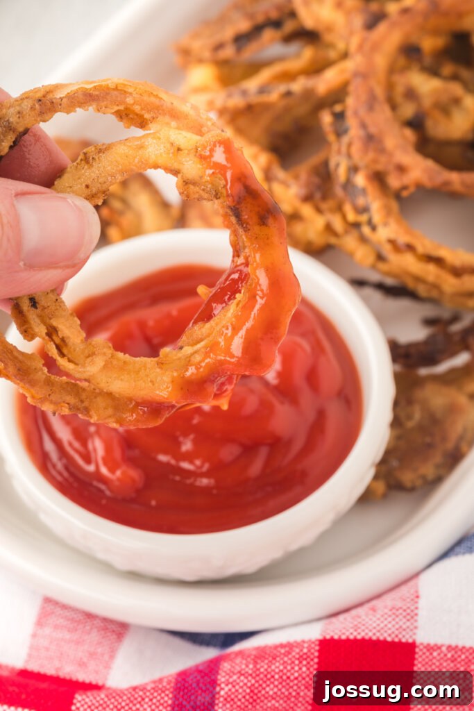 Golden Crispy Onion Rings 4 hand dipping two onion rings into ketchup