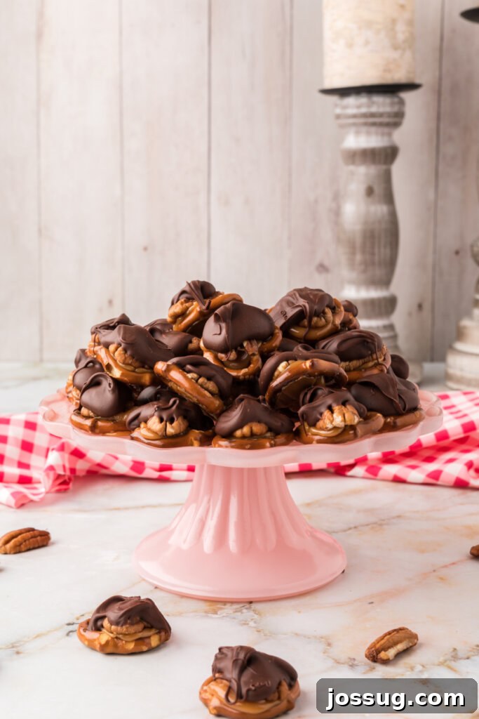 Gooey Caramel Pecan Turtles 4 Close-up of chocolate turtle candies neatly stacked on a pink cake platter, highlighting their perfect form and delicious appeal.