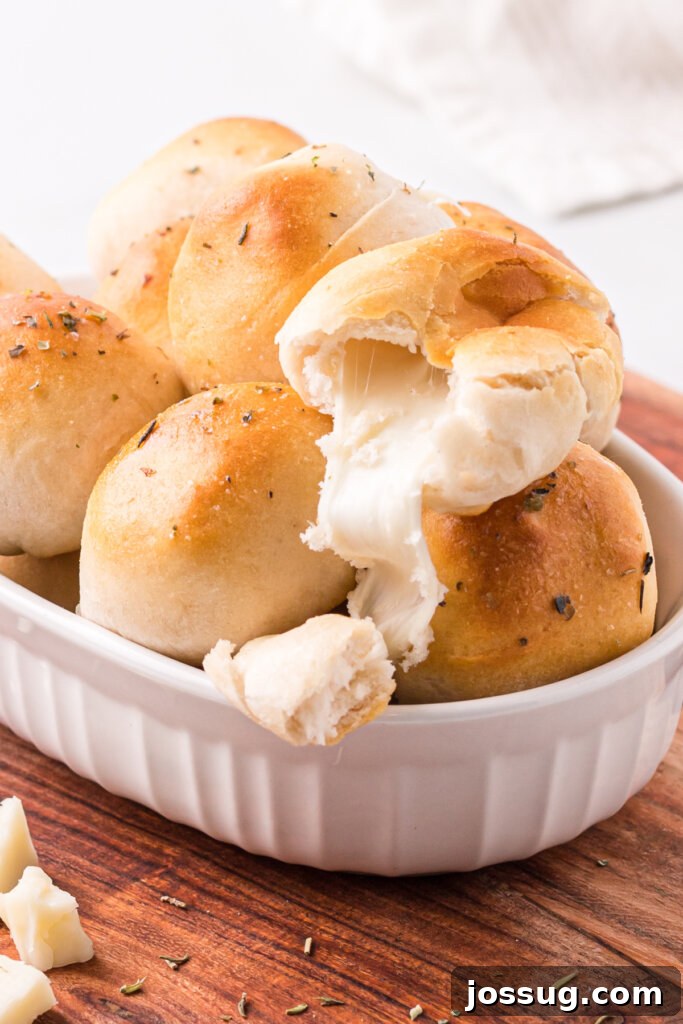 Cheesy Garlic Herb Melt-Aways 2 garlic herb cheese bombs in white serving platter with the top bomb showing the cheese oozing