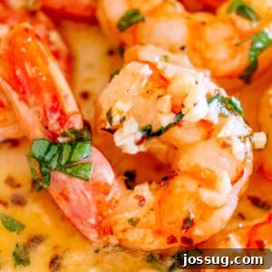 Square image of shrimp generously coated in rich garlic butter, garnished with fresh parsley and surrounded by a pool of golden buttery sauce, ready to be served.
