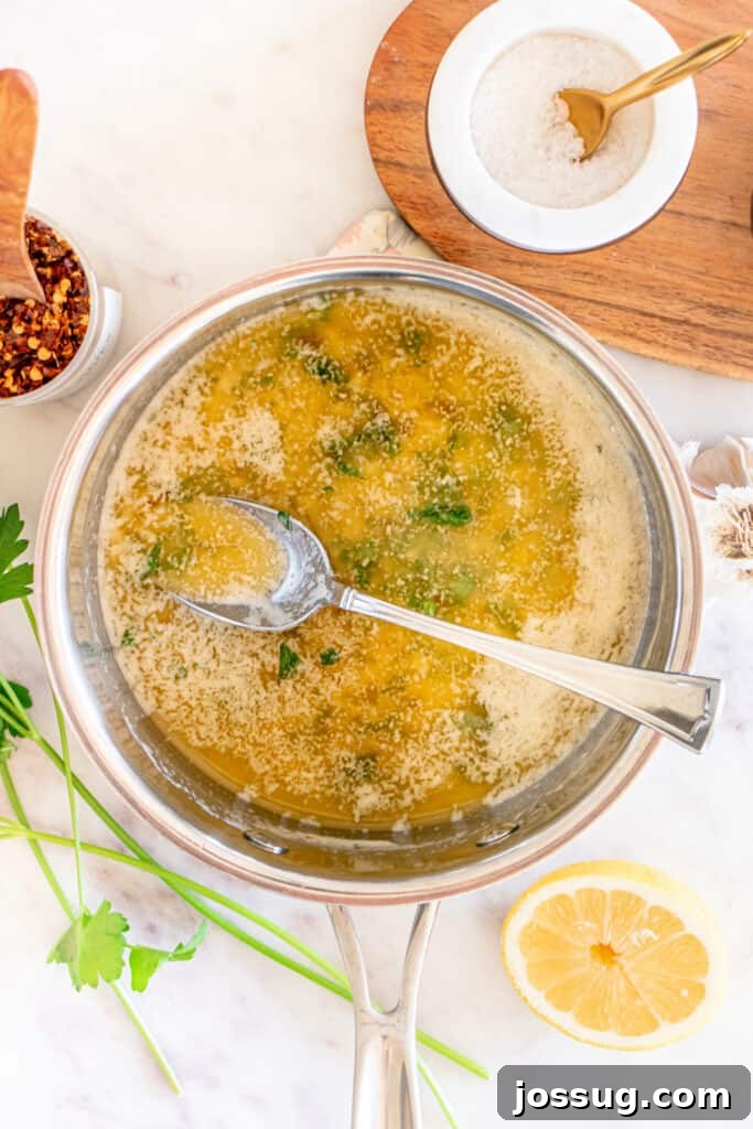 Succulent Air Fryer Garlic Butter Shrimp 8 A luscious garlic butter sauce gently simmering in a saucepan, with fresh, vibrant parsley expertly stirred in. Nearby, bright lemon halves and an array of fragrant seasonings complete the inviting culinary scene.