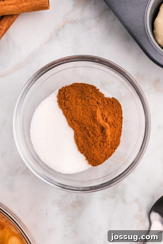 Cinnamon and granulated sugar perfectly combined in a clear glass bowl, ready to generously coat the baked apple pie bombs.