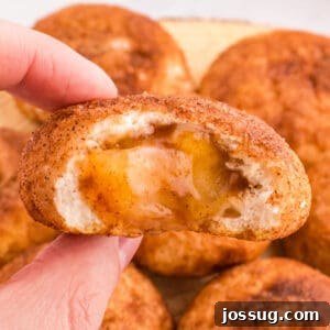 Square image of an apple pie bomb with gooey spiced apple filling inside, held up to show the center.