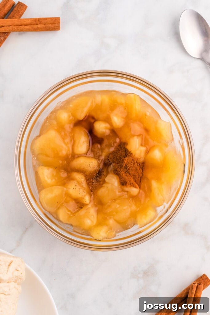 Apple pie filling in a glass bowl, enhanced with cinnamon and vanilla, ready for the apple pie bombs recipe.