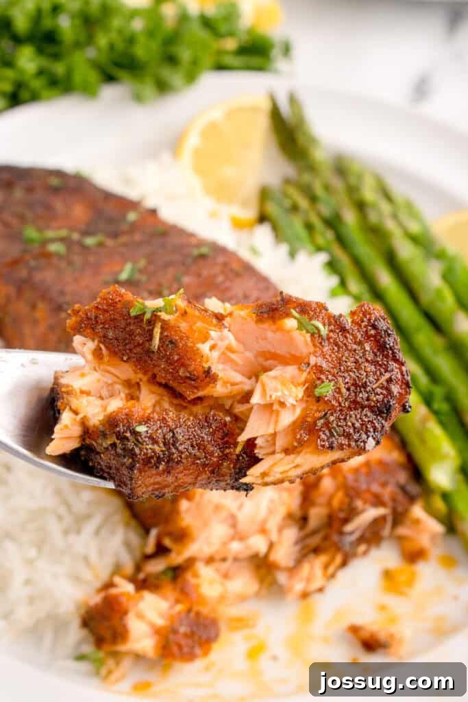 Forkful of flaky blackened salmon showing tender inside texture.