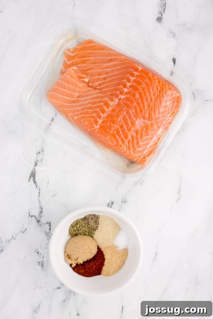 Fresh salmon fillets in packaging with a small bowl of blackened seasoning spices.