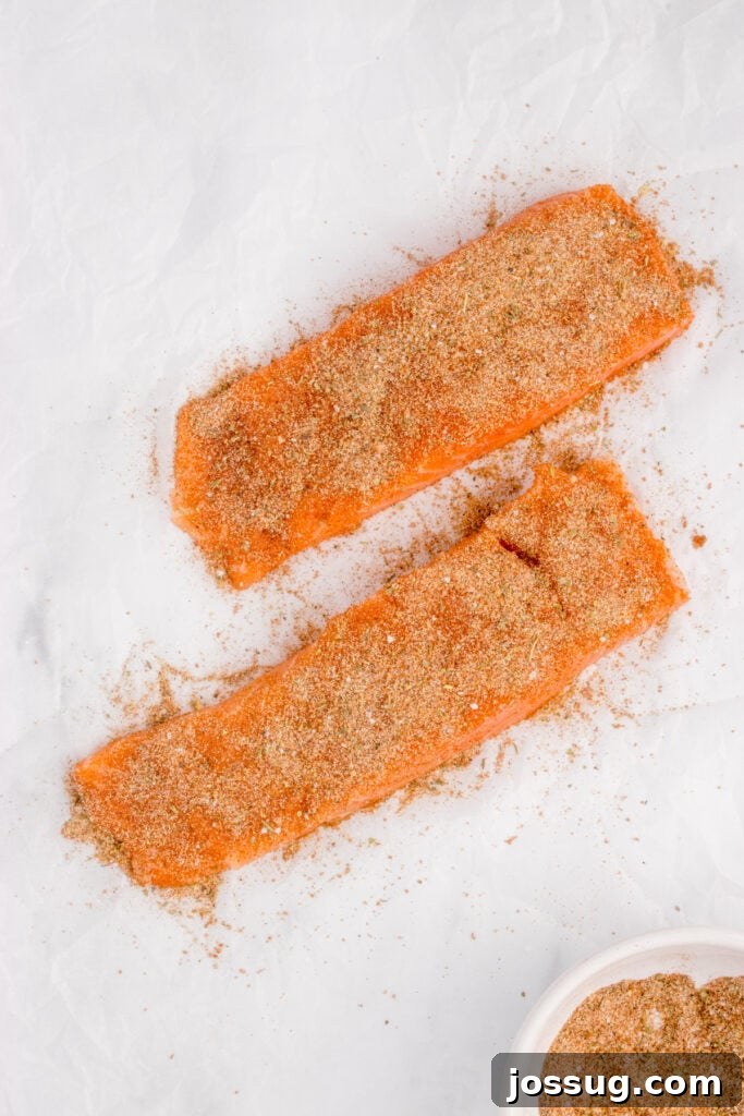 Salmon fillets coated with blackened seasoning before cooking.