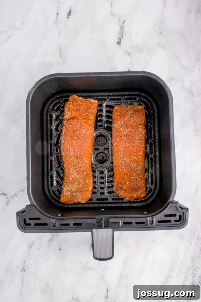 Salmon fillets placed in the air fryer basket before cooking.