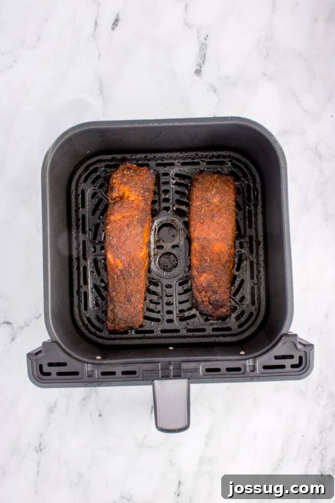 Cooked blackened salmon fillets in the air fryer basket after air frying.