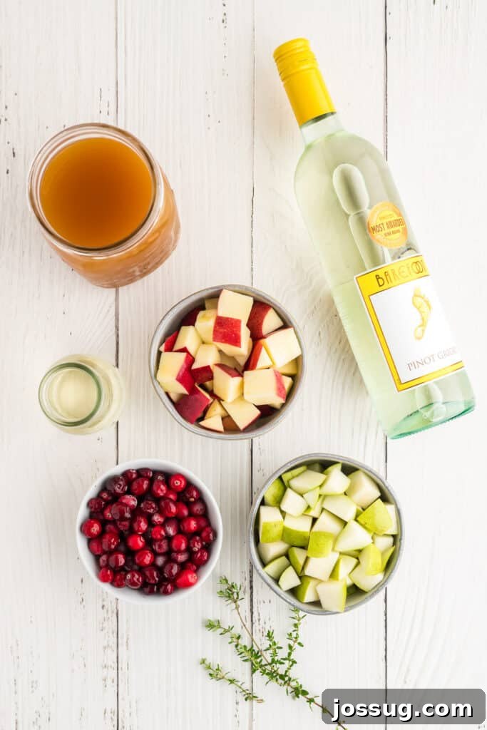 Autumn Orchard Sangria 3 Overhead view of ingredients for apple cider sangria including apples, pears, cranberries, wine, and apple cider