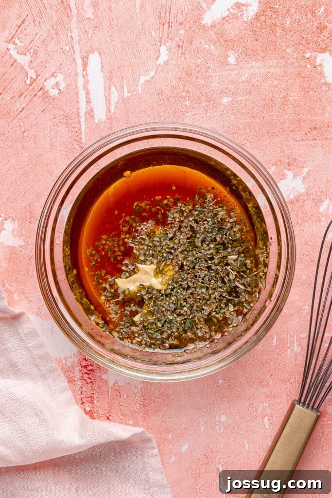 Grinding Bean Power Salad 5 Small glass bowl with vinaigrette ingredients including oil, vinegar, mustard, garlic, and Italian seasoning before whisking.