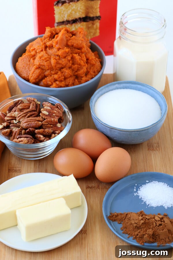 Spiced Pumpkin Crumble Bake 4 A flat lay of all the essential ingredients for making Pumpkin Dump Cake, including cans of pumpkin and evaporated milk, eggs, sugar, spices, a box of cake mix, butter, and pecans.
