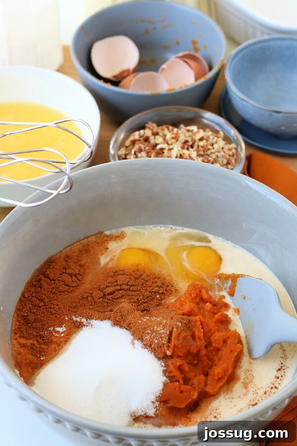 Spiced Pumpkin Crumble Bake 5 A large mixing bowl containing the wet ingredients for the pumpkin layer – pumpkin puree, evaporated milk, eggs, sugar, salt, and cinnamon – ready to be whisked together.